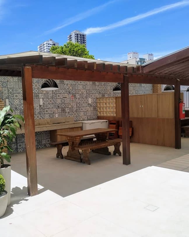 Churrasqueira e mesa sob o pergolado na área comum revitalizada pela Simo Engenharia